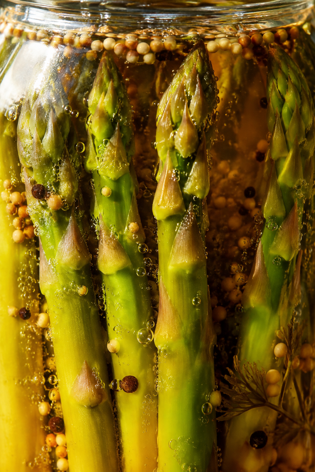 Green asparagus spears in golden brine